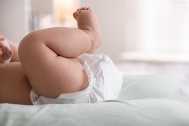 Photo of Cute little baby in diaper on bed indoors, closeup. Space for text