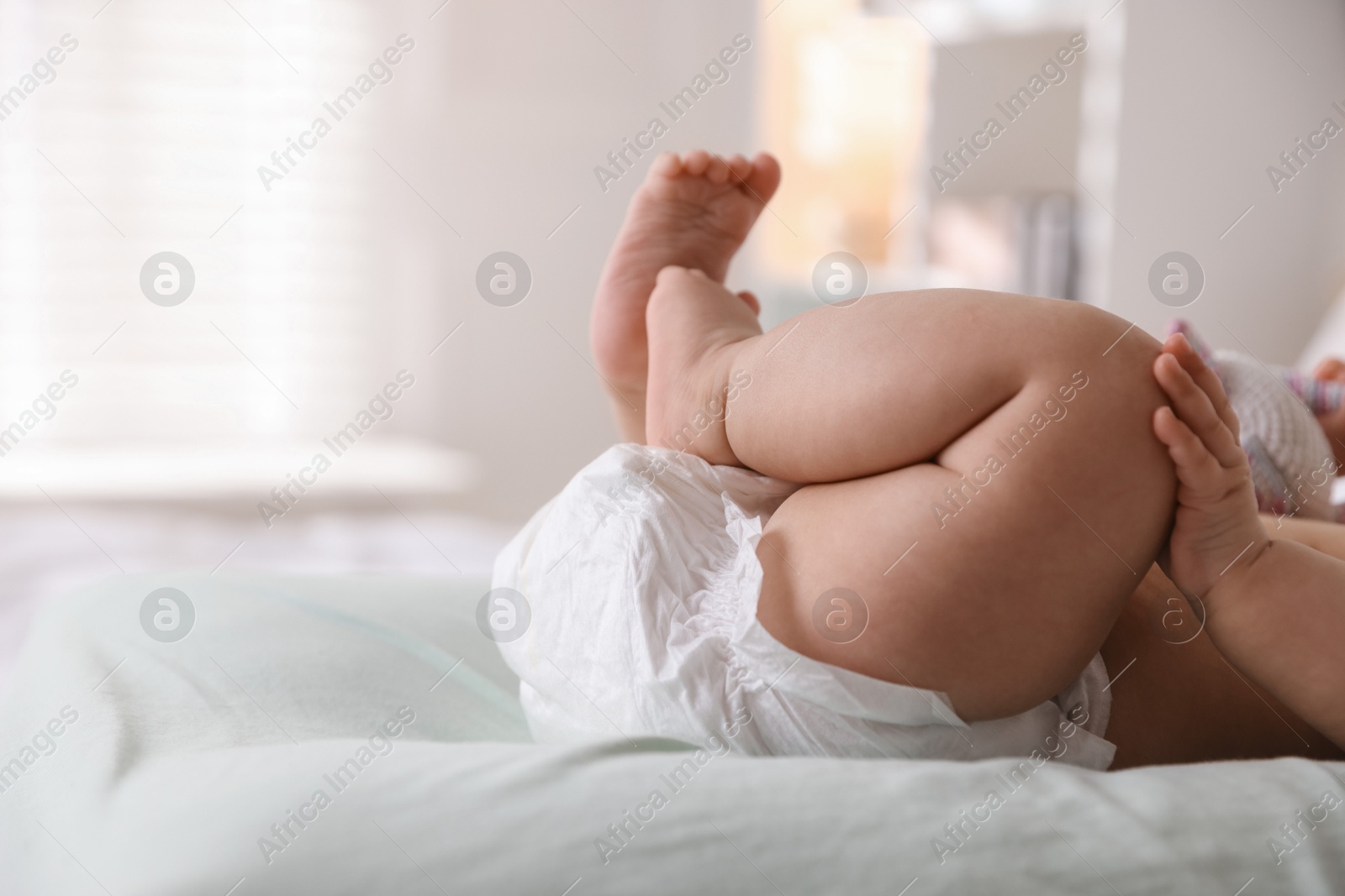 Photo of Cute little baby in diaper on bed indoors, closeup. Space for text