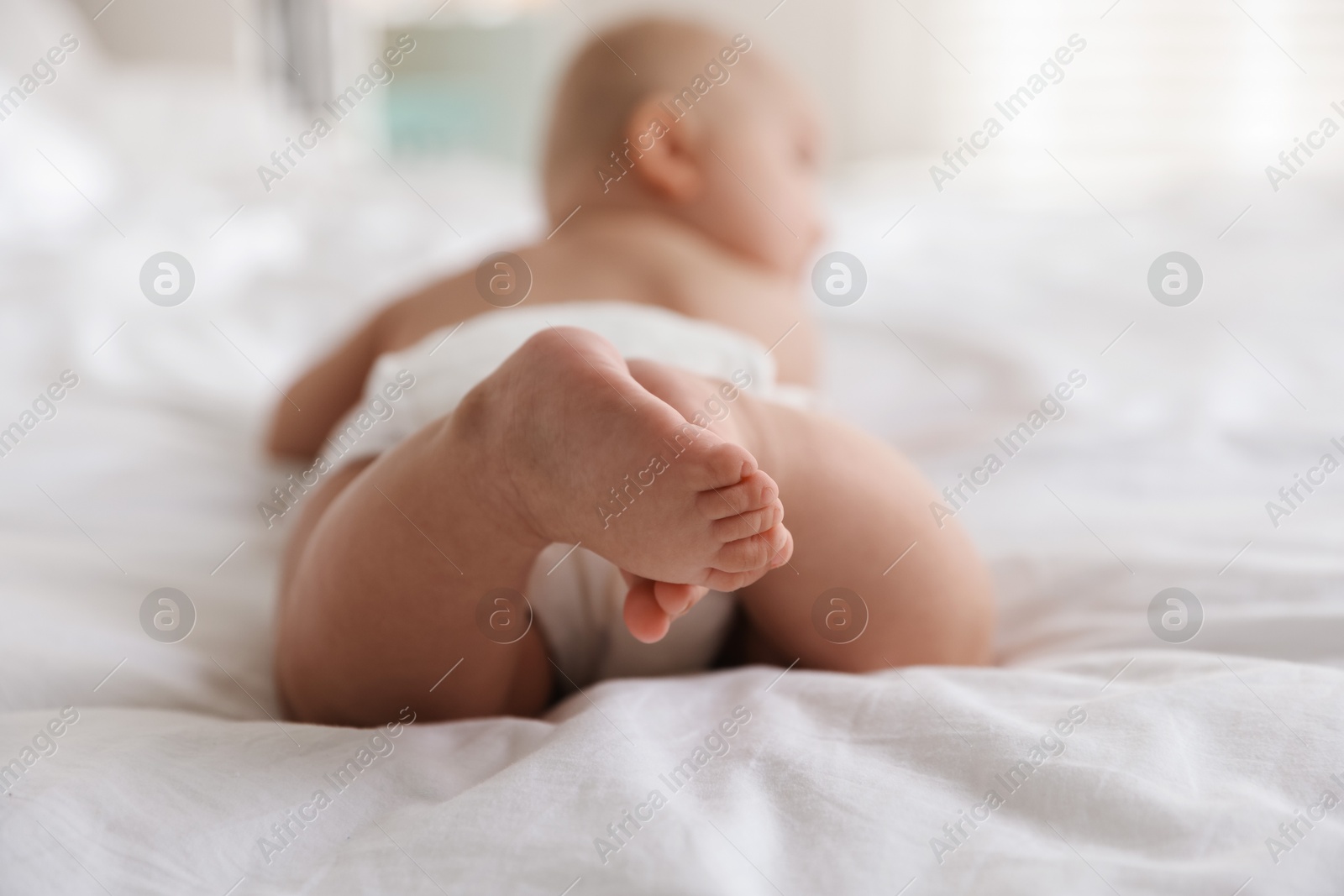 Photo of Cute little baby in diaper on bed indoors, selective focus