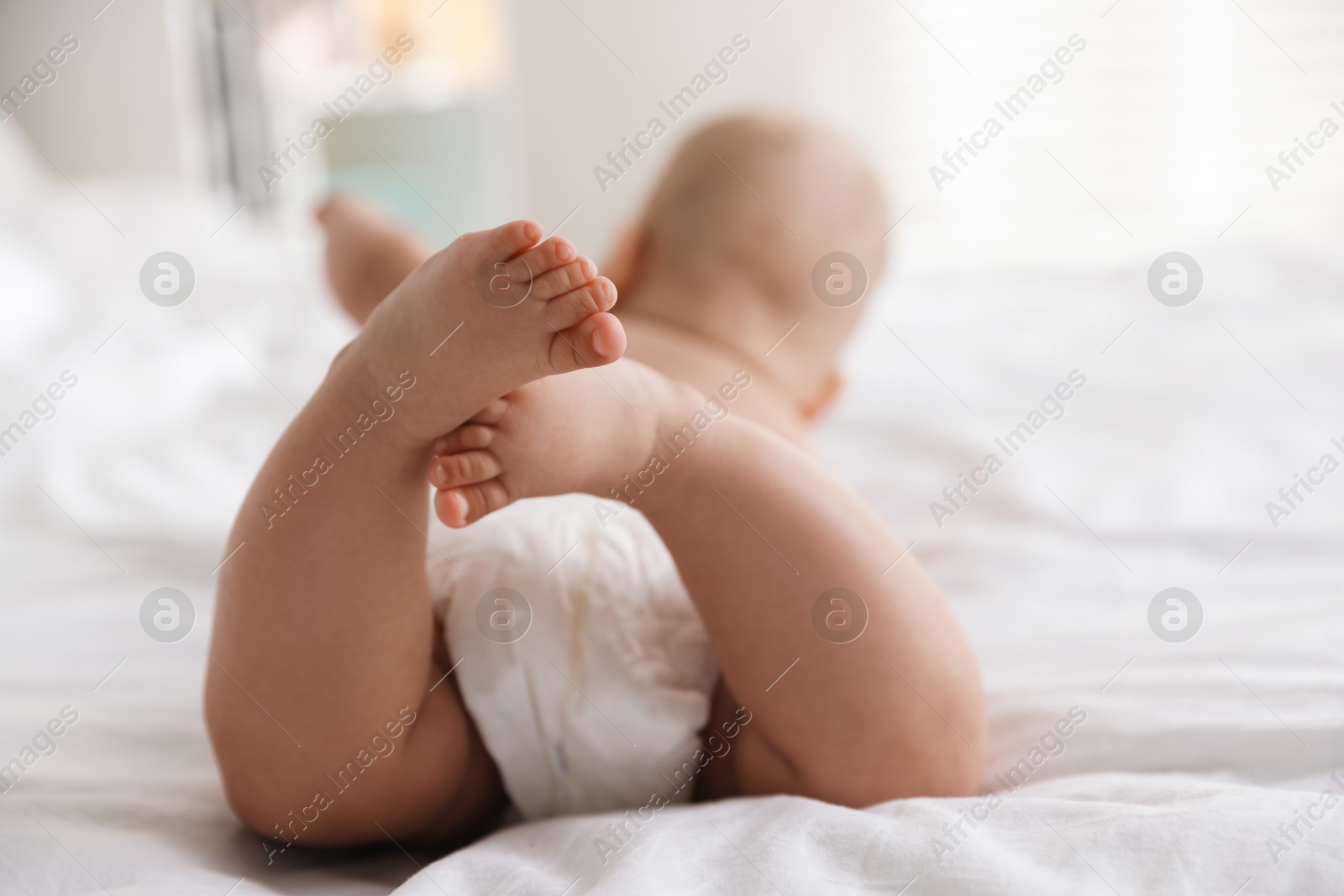 Photo of Cute little baby in diaper on bed indoors, selective focus