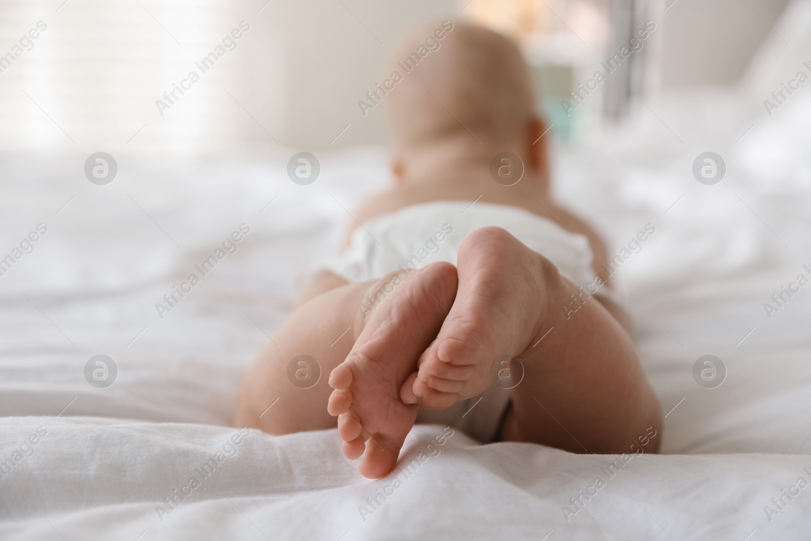 Photo of Cute little baby in diaper on bed indoors, selective focus