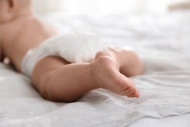 Photo of Cute little baby in diaper on bed, selective focus