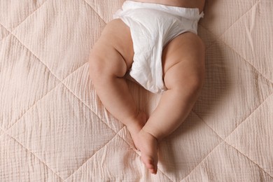 Photo of Cute little baby in diaper on bed, top view