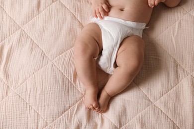 Photo of Cute little baby in diaper on bed, top view