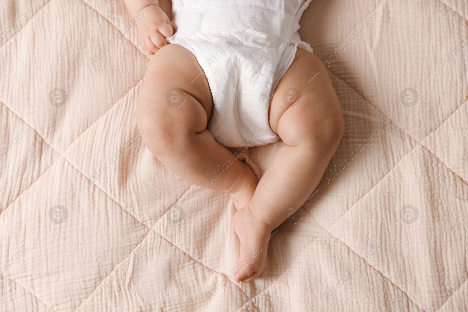 Photo of Cute little baby in diaper on bed, top view