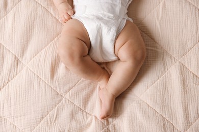 Cute little baby in diaper on bed, top view