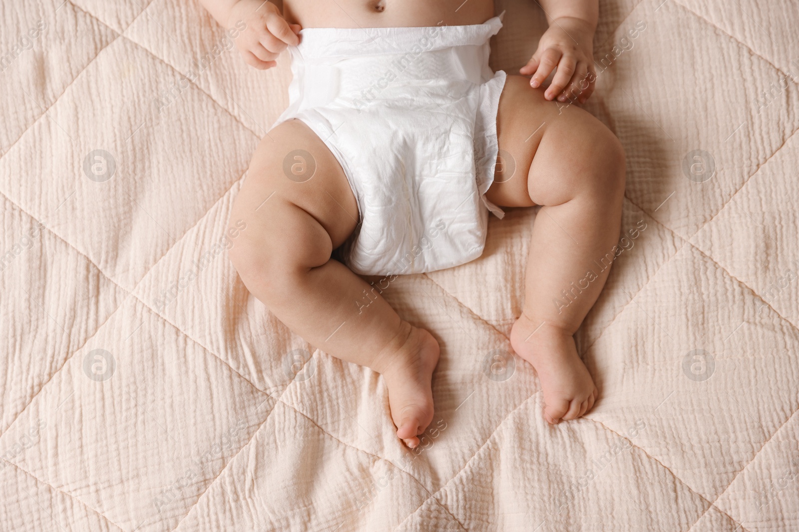 Photo of Cute little baby in diaper on bed, top view