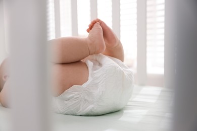 Photo of Little baby wearing diaper in crib, closeup