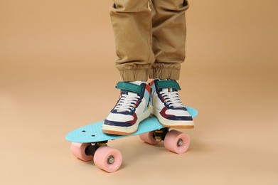 Photo of Little boy with skateboard on beige background, closeup