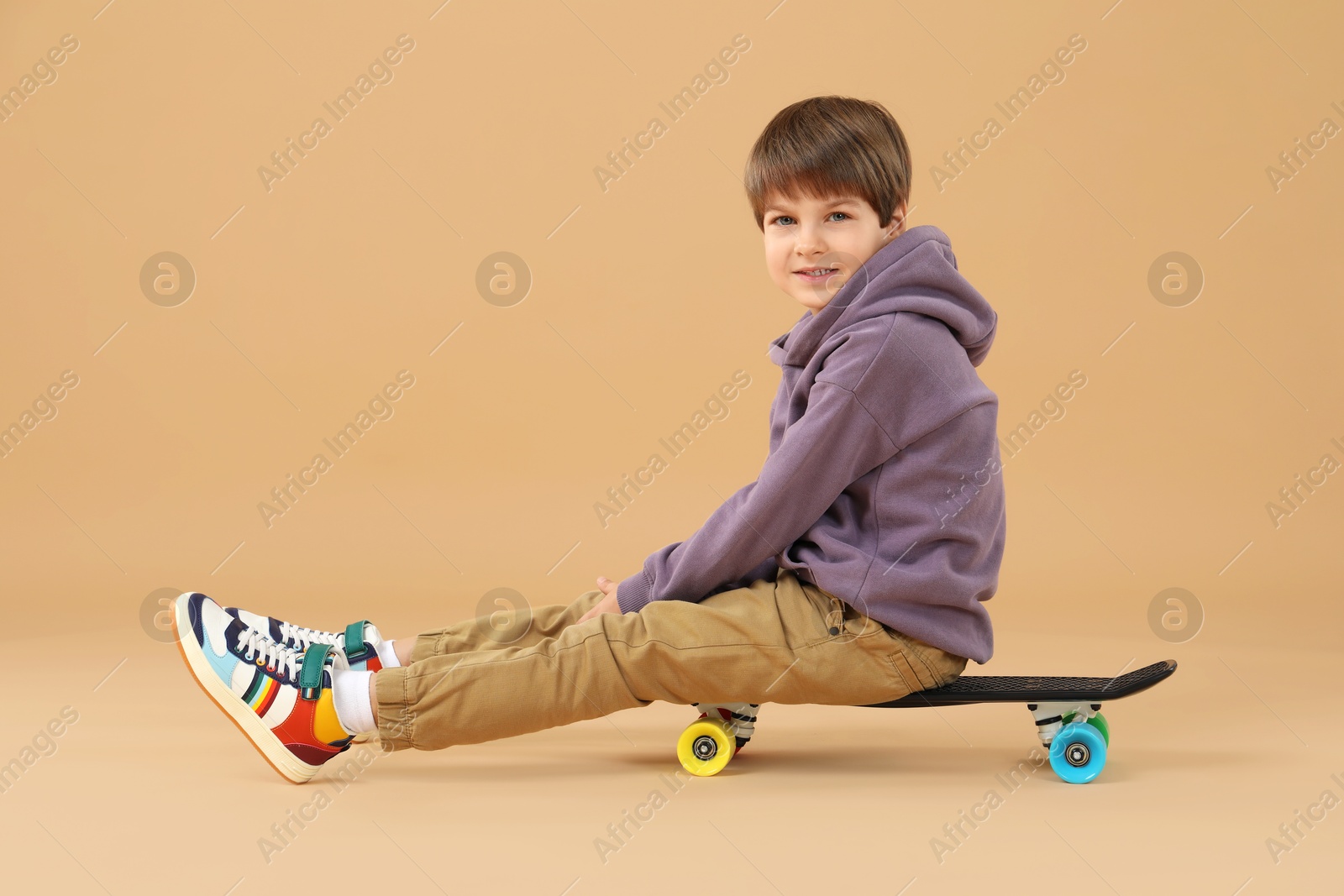 Photo of Little boy with skateboard on beige background