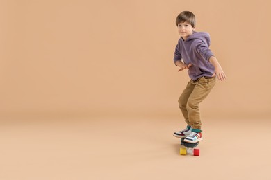 Photo of Little boy with skateboard on beige background, space for text