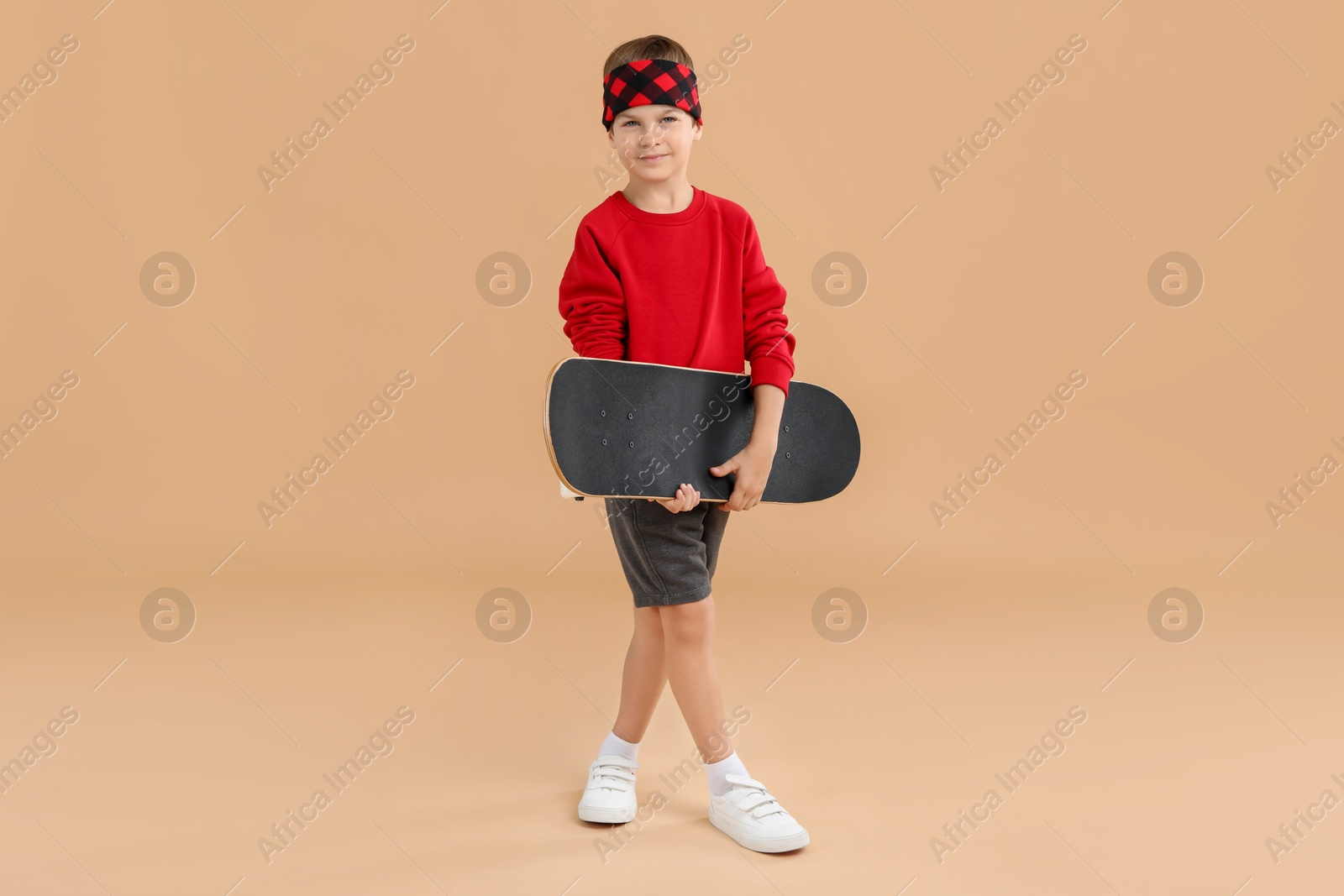 Photo of Little boy with skateboard on beige background