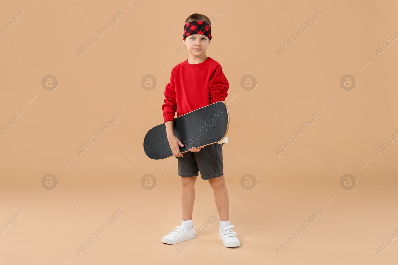 Photo of Little boy with skateboard on beige background