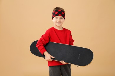 Little boy with skateboard on beige background