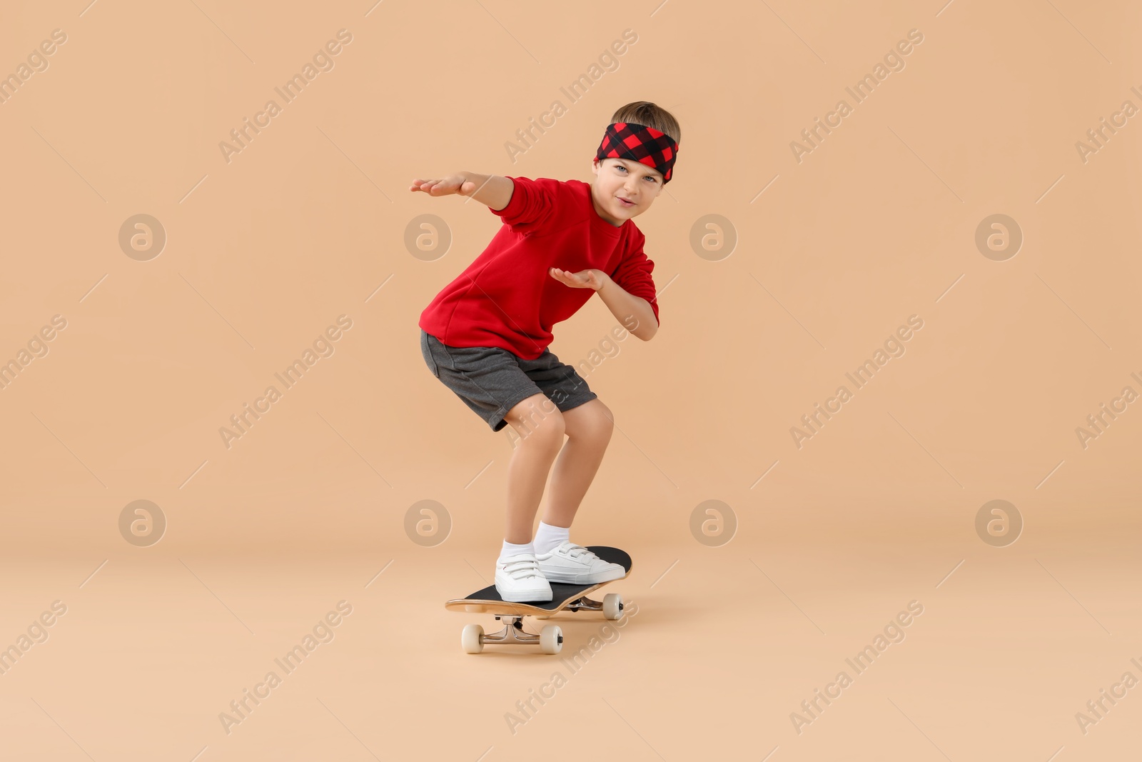 Photo of Little boy with skateboard on beige background