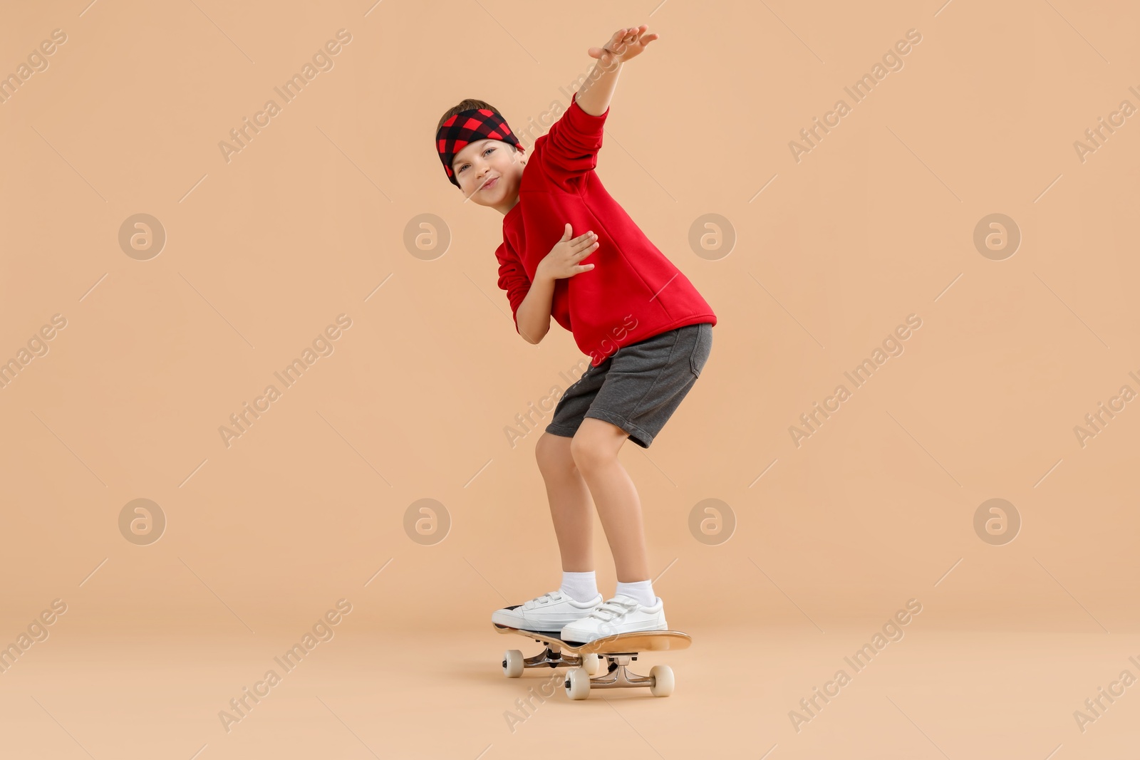 Photo of Little boy with skateboard on beige background