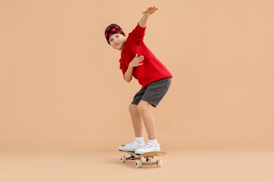 Photo of Little boy with skateboard on beige background