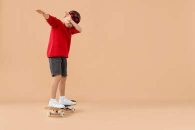 Photo of Little boy with skateboard on beige background, space for text