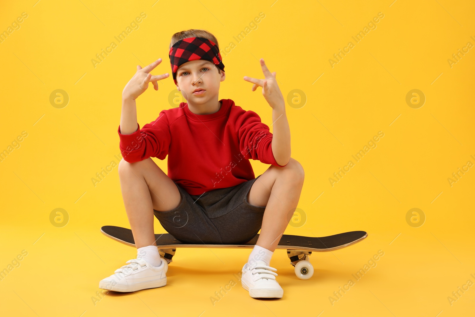 Photo of Little boy with skateboard on yellow background