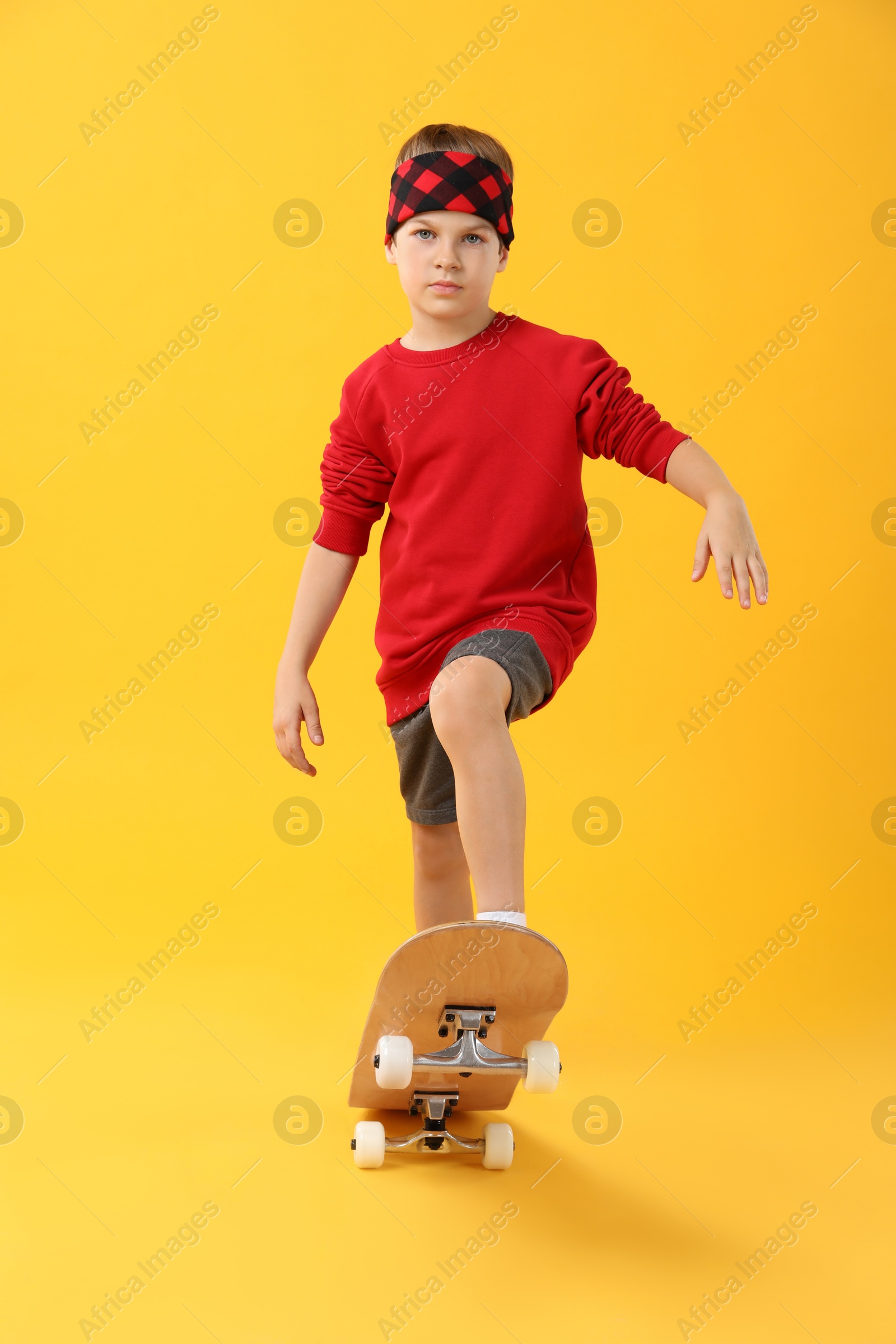 Photo of Little boy with skateboard on yellow background