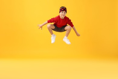 Photo of Happy little boy jumping on yellow background