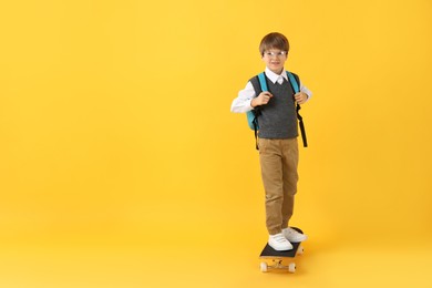 Photo of Little boy with skateboard on yellow background, space for text