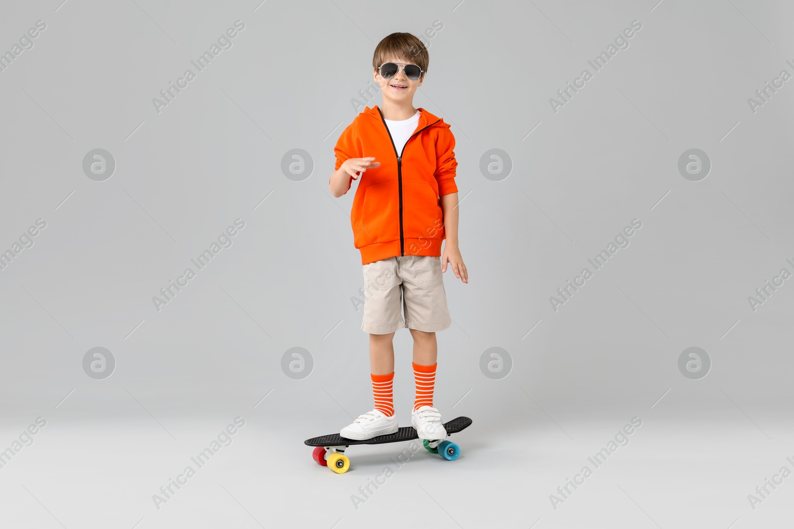 Photo of Little boy with skateboard on light grey background