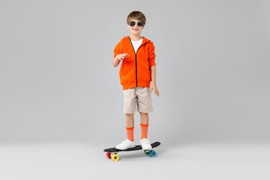 Photo of Little boy with skateboard on light grey background