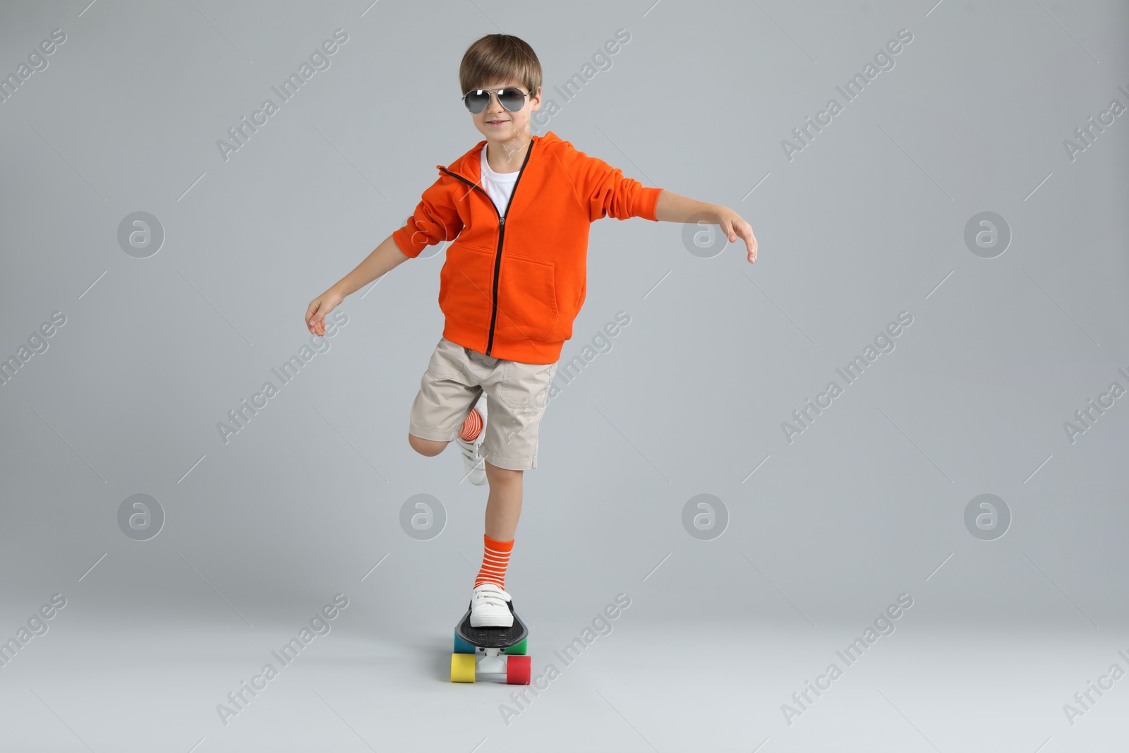 Photo of Little boy with skateboard on light grey background