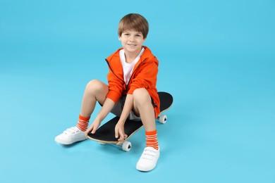 Photo of Little boy with skateboard on light blue background