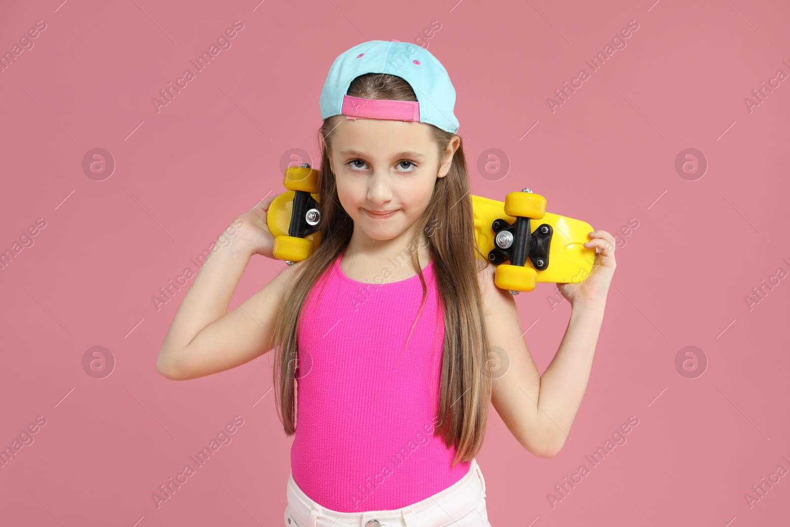 Photo of Little girl with penny board on pink background