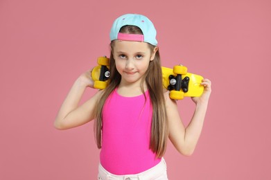 Photo of Little girl with penny board on pink background