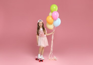 Photo of Little girl with colorful balloons and penny board on pink background