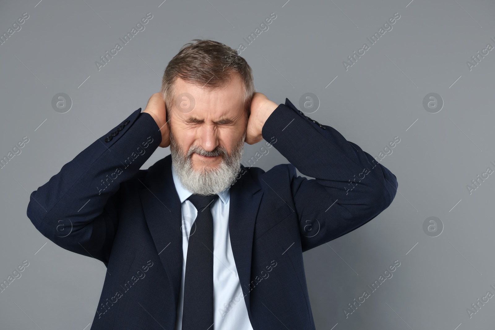 Photo of Senior man covering his ears on grey background