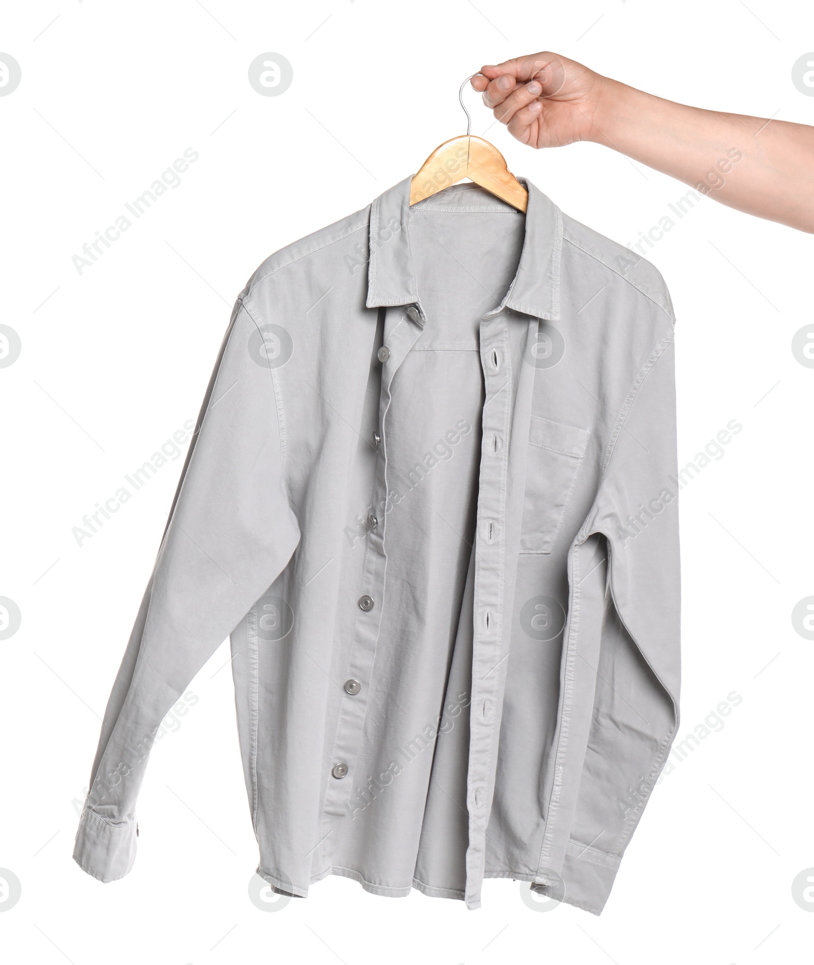 Photo of Woman holding hanger with light grey shirt on white background, closeup