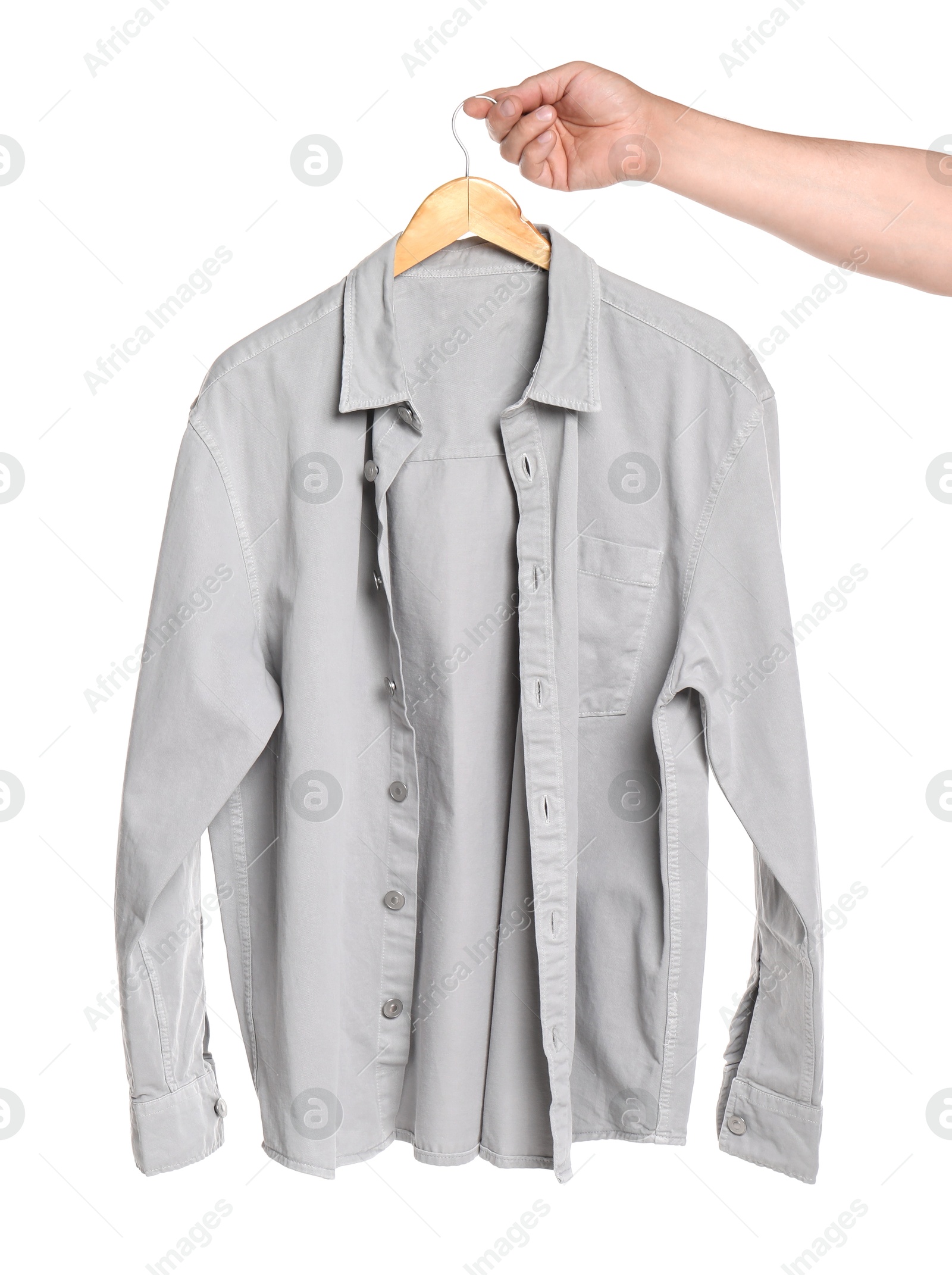 Photo of Woman holding hanger with light grey shirt on white background, closeup