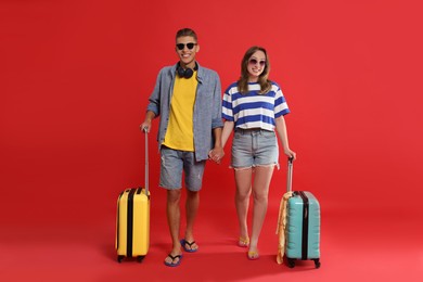 Photo of Happy travellers with suitcases on red background