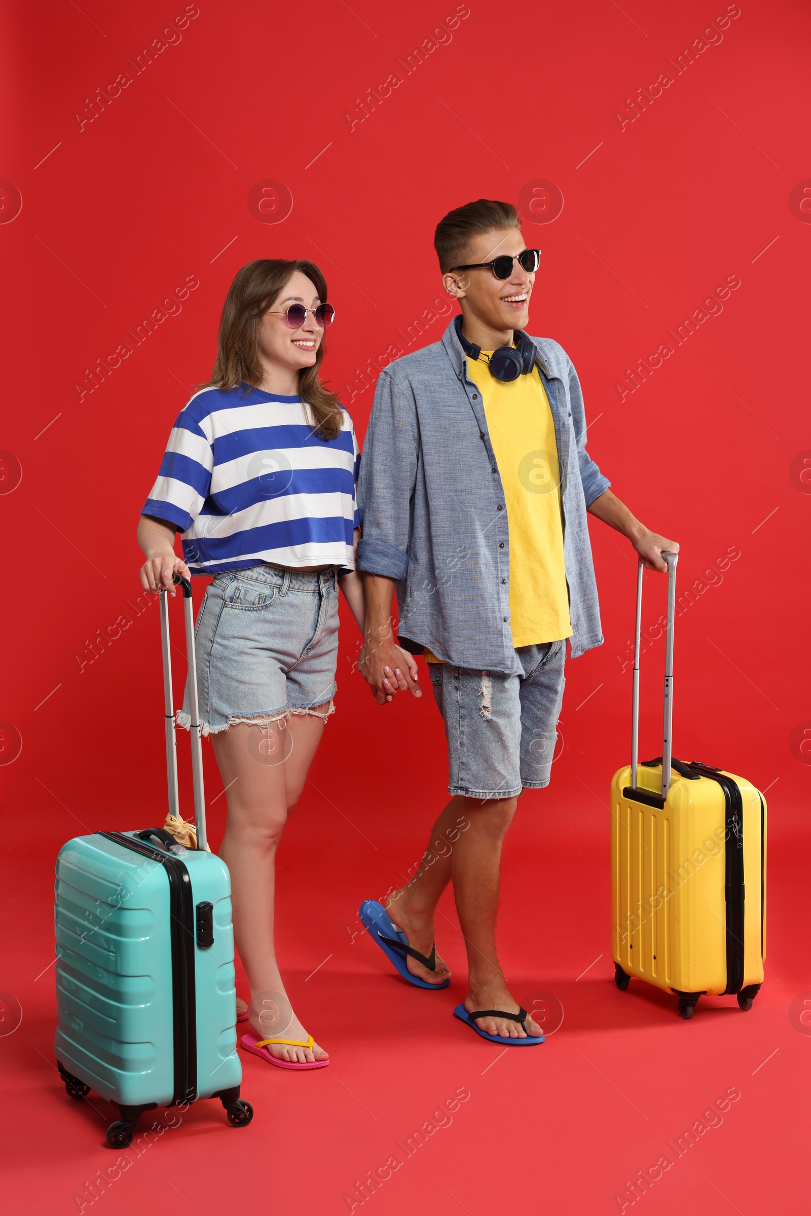 Photo of Happy travellers with suitcases on red background