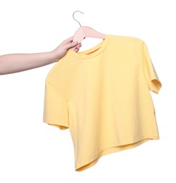 Photo of Woman holding hanger with yellow t-shirt on white background, closeup