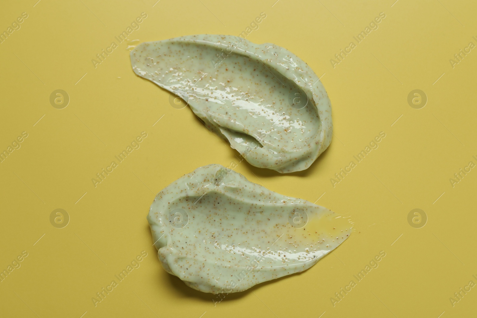 Photo of Smears of body scrub on yellow background, top view