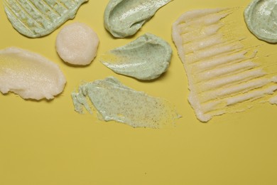 Photo of Samples of different body scrubs on yellow background, top view