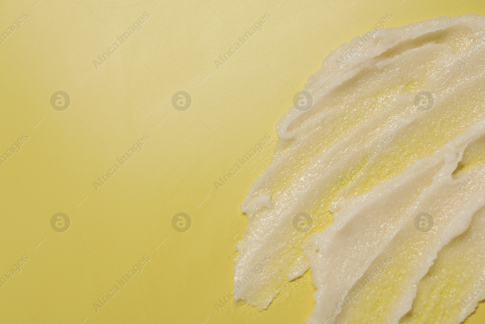 Photo of Sample of body scrub on yellow background, top view. Space for text