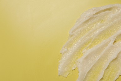 Photo of Sample of body scrub on yellow background, top view. Space for text