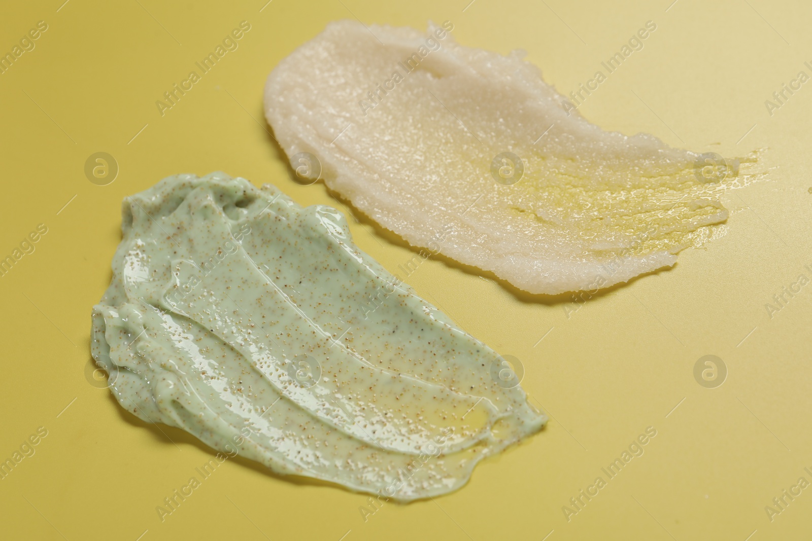 Photo of Samples of different body scrubs on yellow background, closeup