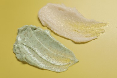 Photo of Samples of different body scrubs on yellow background, closeup