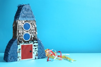 Photo of Beautiful pinata in shape of rocket on blue background. Space for text