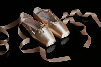 Photo of Pair of beautiful pointe shoes on black mirror surface