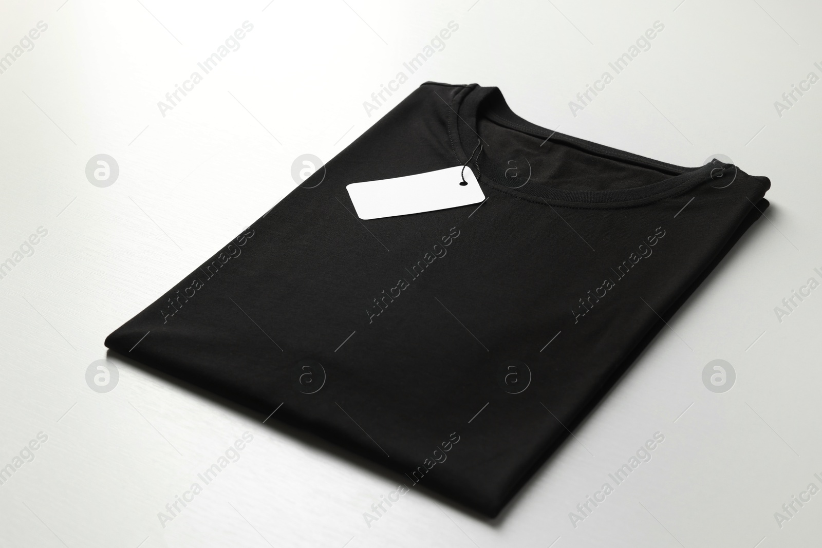 Photo of Blank black t-shirt on white background, closeup. Mockup for design