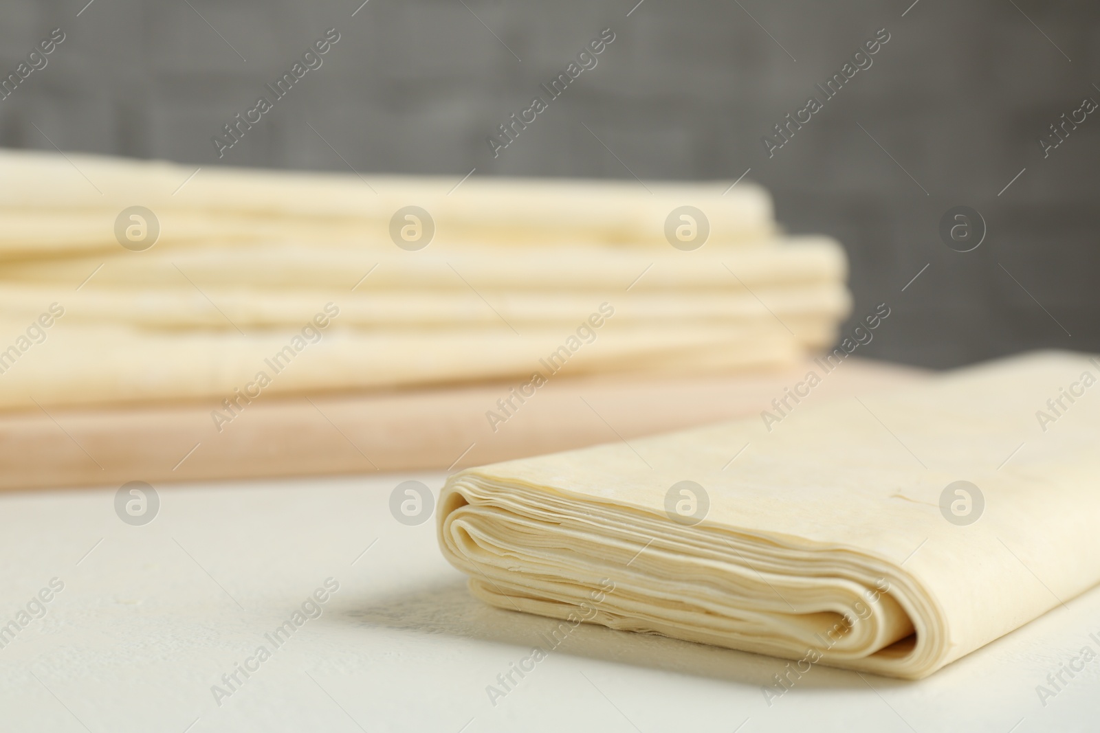 Photo of Raw puff pastry dough on white table, closeup. Space for text