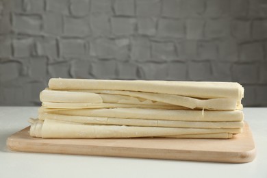 Photo of Stack of raw puff pastry dough on white table, closeup